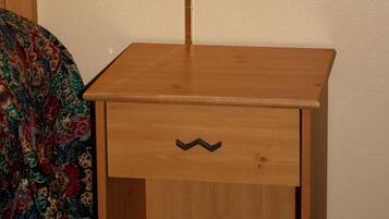 A wooden nightstand with a lamp, a drawer, and a patterned bedspread.