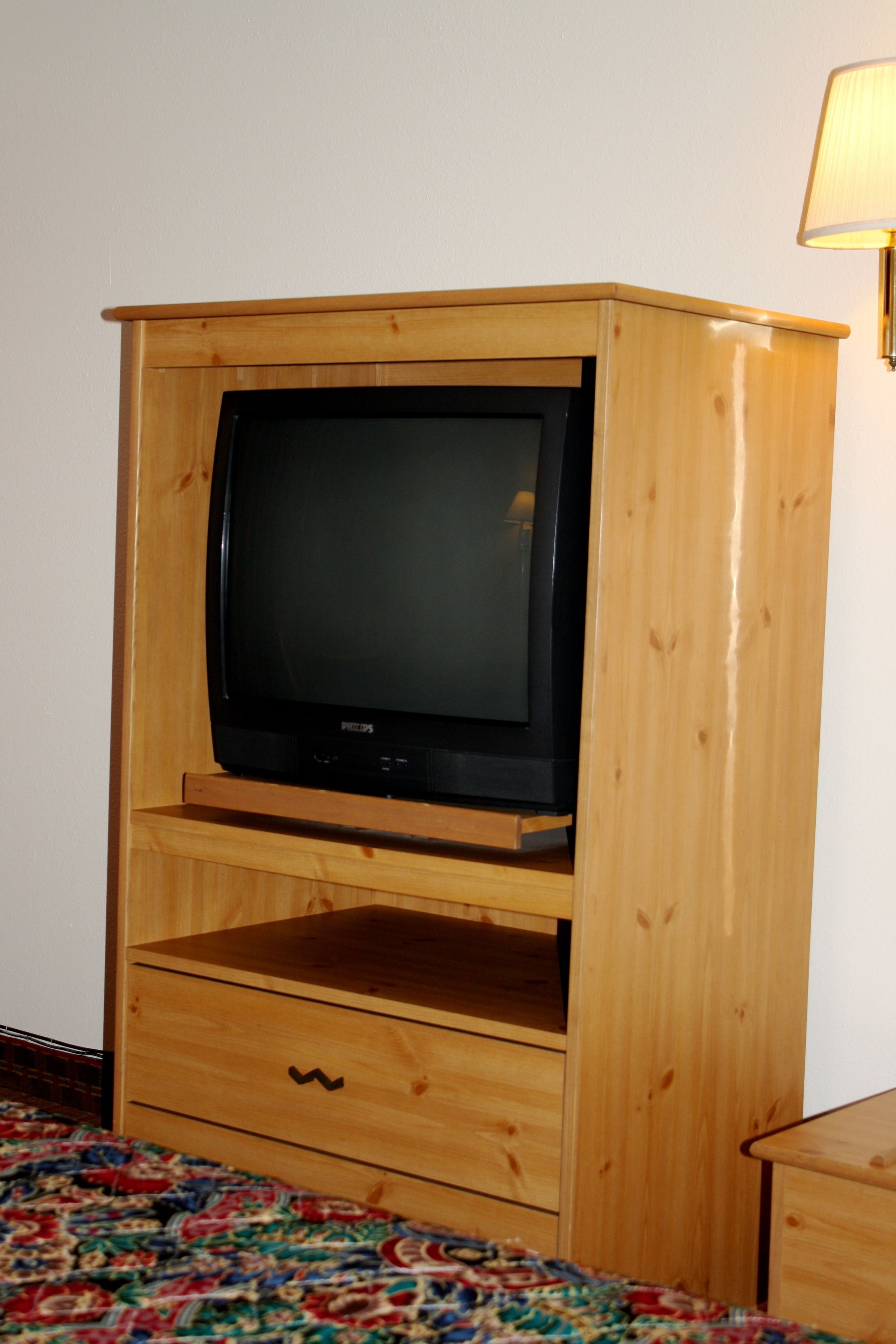 Un mueble de madera con espacio para televisión, un cajón y una lámpara.