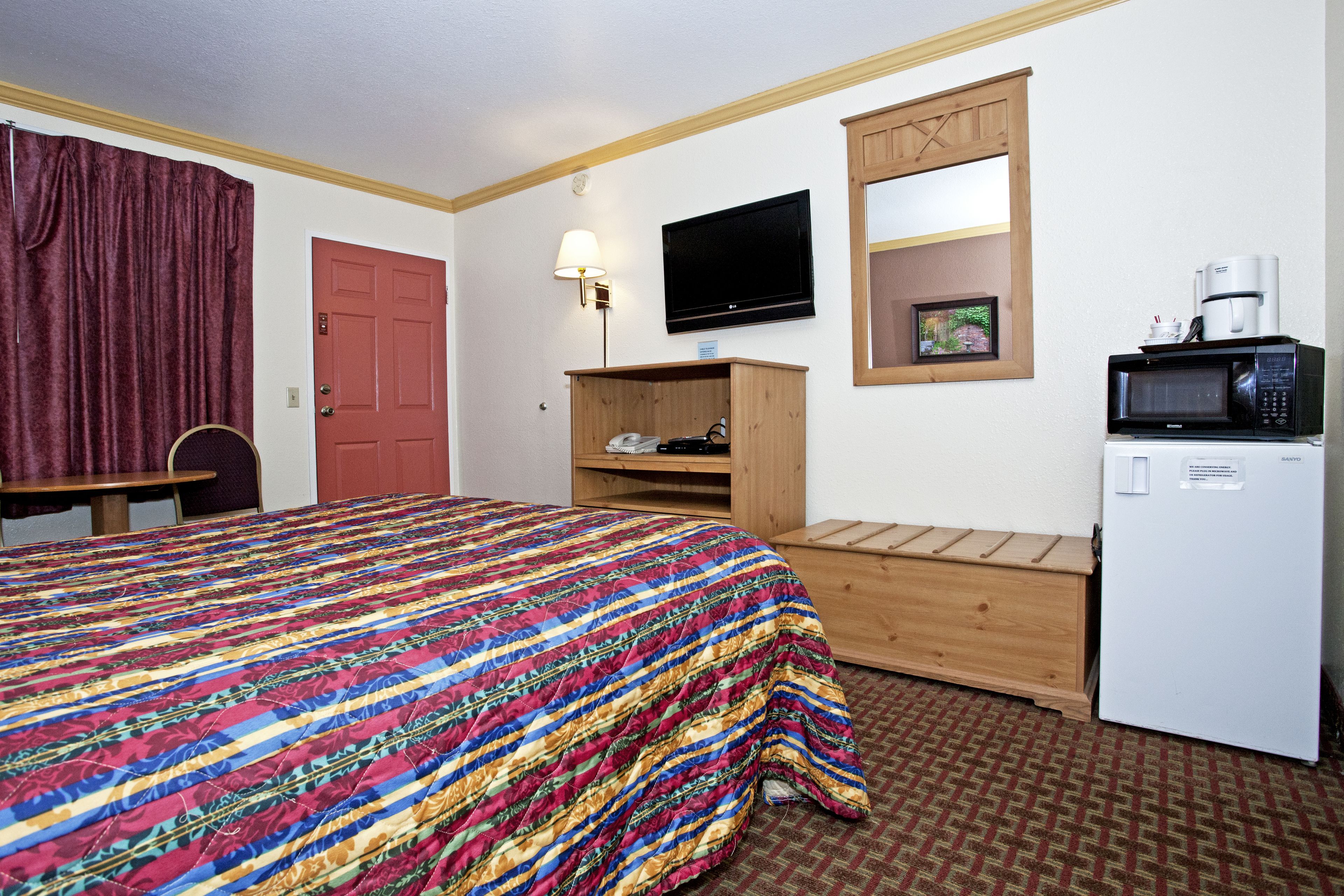 Una habitación de hotel con una cama, un escritorio, un televisor, un microondas y un refrigerador.