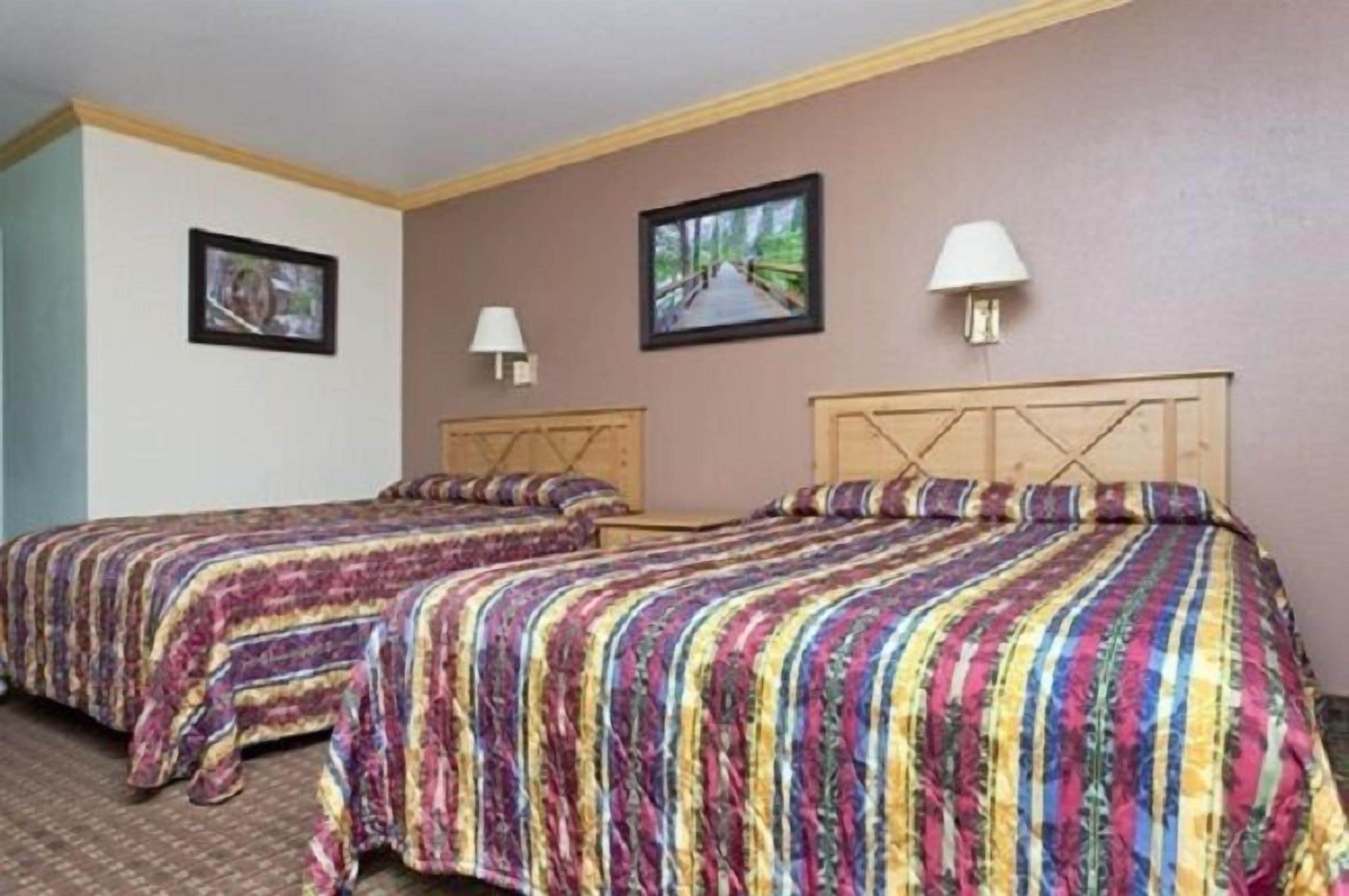 Een hotelkamer met twee bedden, elk met een gestreept dekbedovertrek, een houten hoofdeinde en een inlijsting foto aan de muur.
