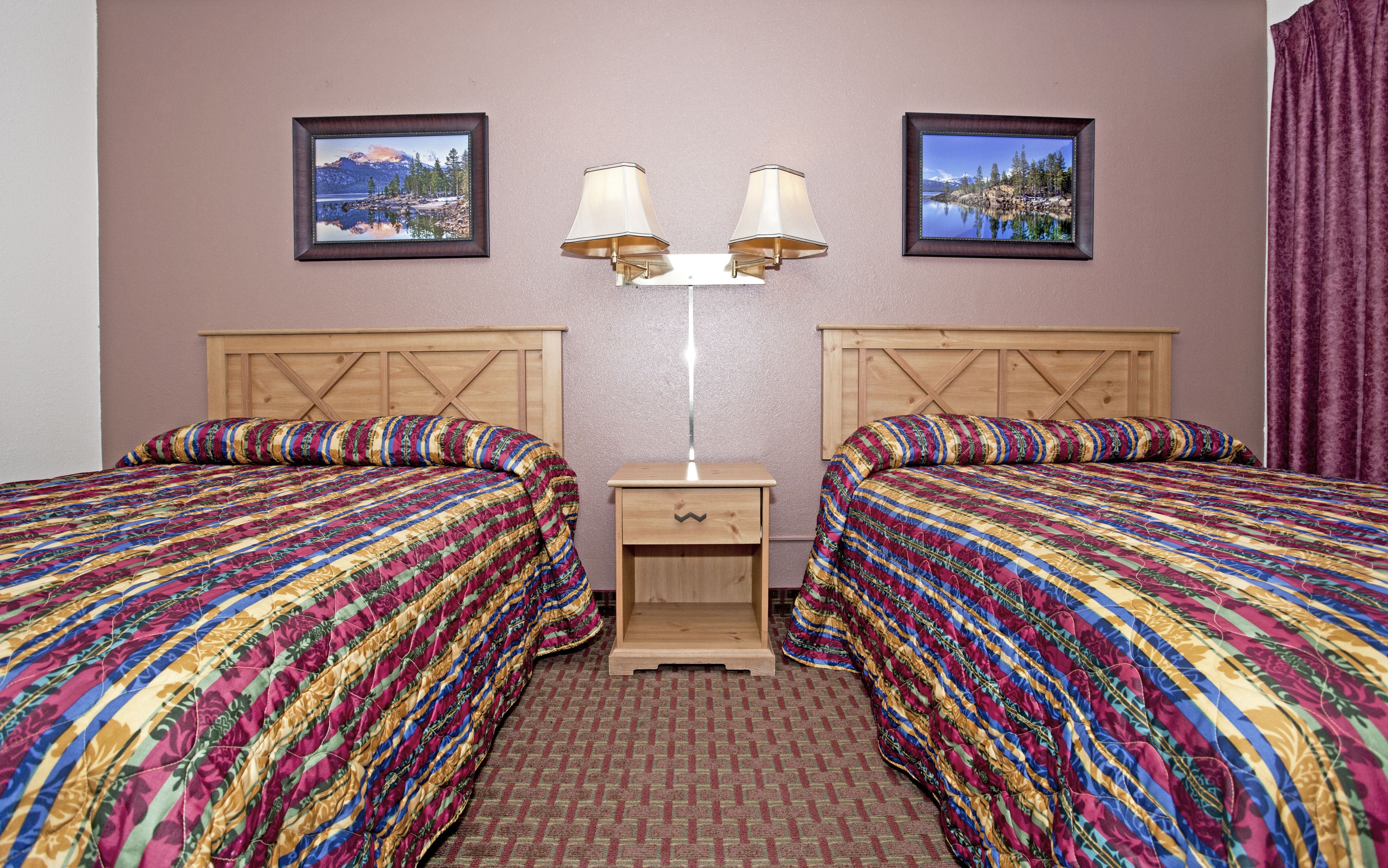 Een hotelkamer met twee bedden, een nachtkastje en twee wandlampen.
