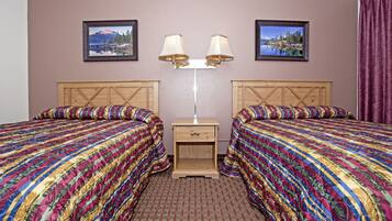 Habitación de hotel con dos camas, una mesita de noche y dos lámparas fijadas a la pared.