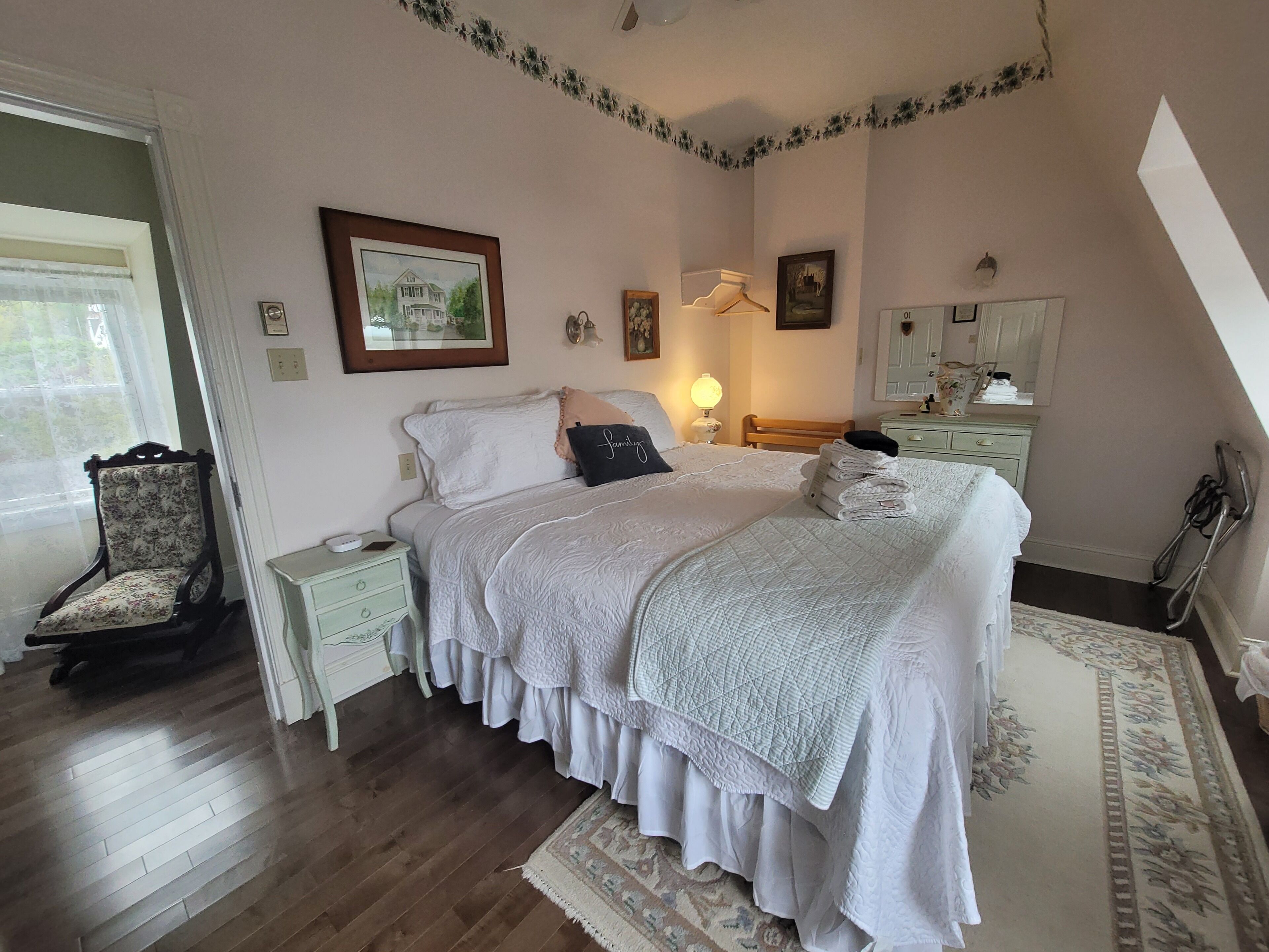 A bedroom with a bed, bedside tables, a chair, a dresser, and a mirror.
