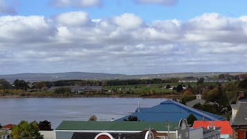 Un pueblo a orillas del río, con edificios a lo largo de la orilla, cielo despejado y vistas lejanas de colinas.