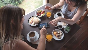 Una mesa de comedor con platos de comida, vasos y un teléfono inteligente.