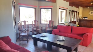 Una sala de estar con un sofá rojo, sillas de madera, una mesa de centro de madera oscura y un sofá rojo.
