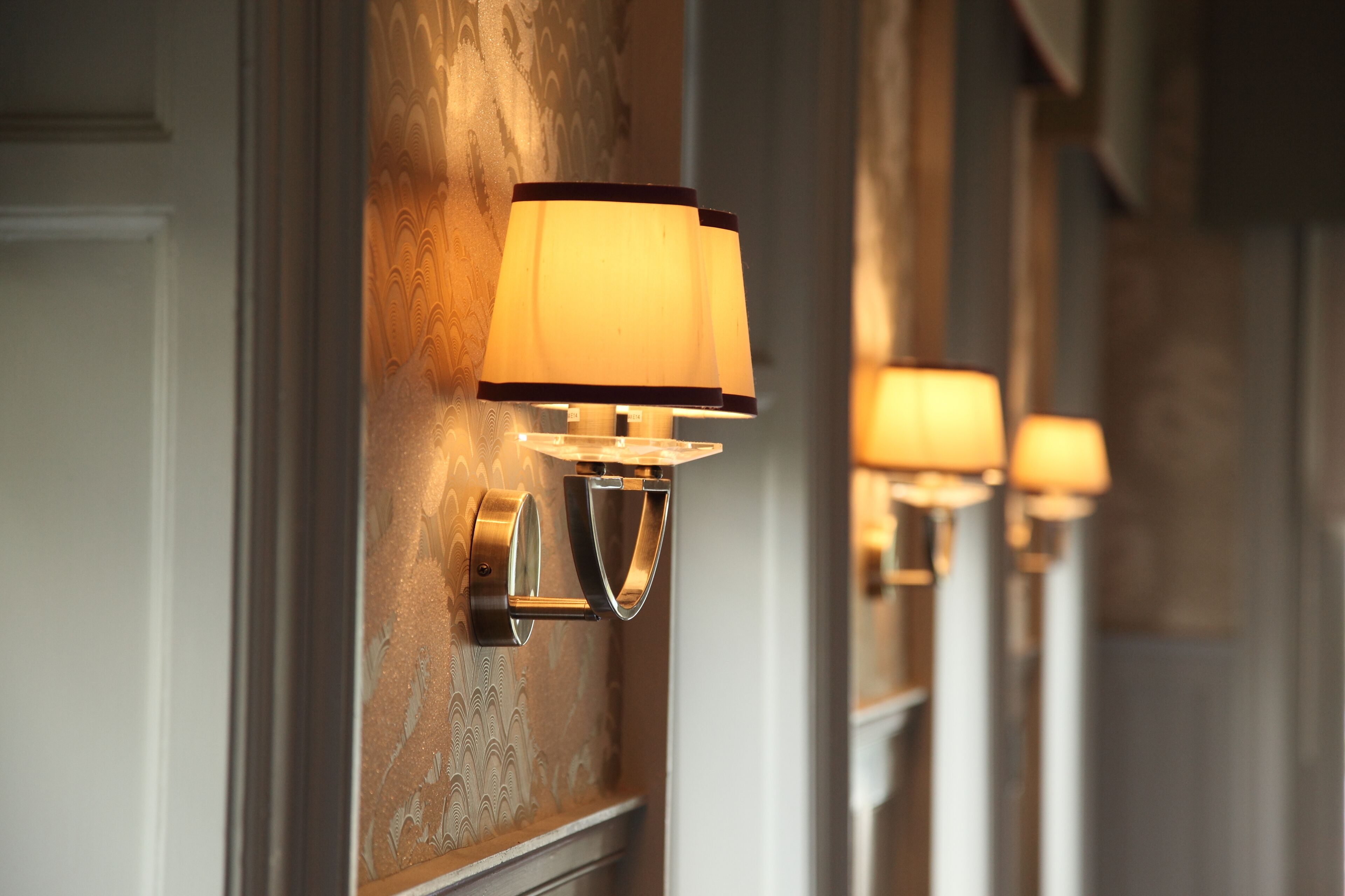 Wall-mounted lamps with a warm light in a hallway.