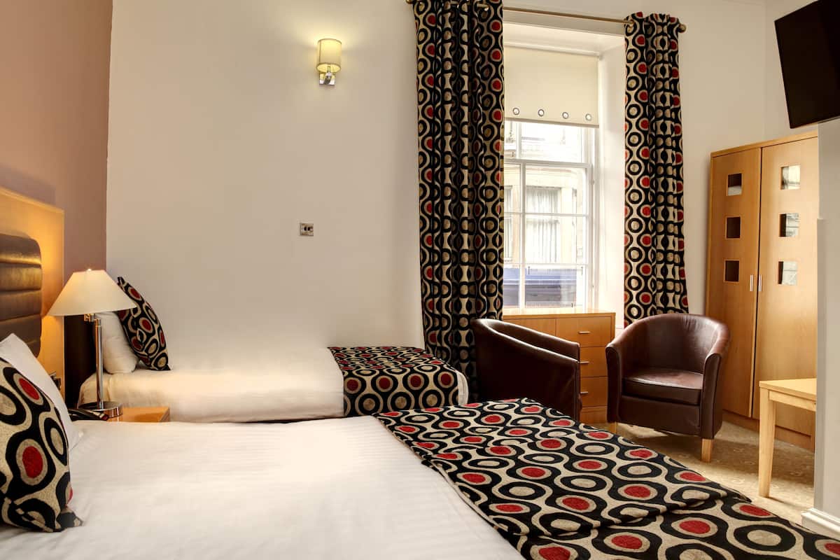 Ein Hotelzimmer mit zwei Betten, einem Schreibtisch, einem Stuhl und einem Kleiderschrank.