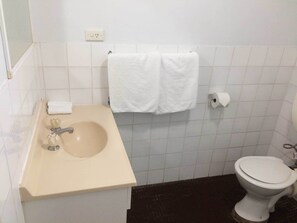 A bathroom with a sink, two towels, a toilet, and a roll of toilet paper. - Villa Shangri-La (Cairns North)