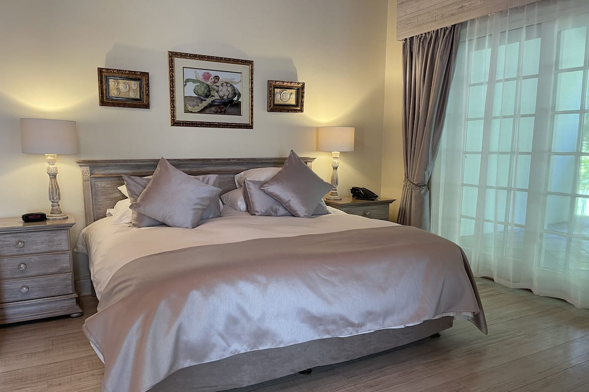 A neatly made bed with a headboard, two bedside tables with lamps, and framed artwork on the wall.