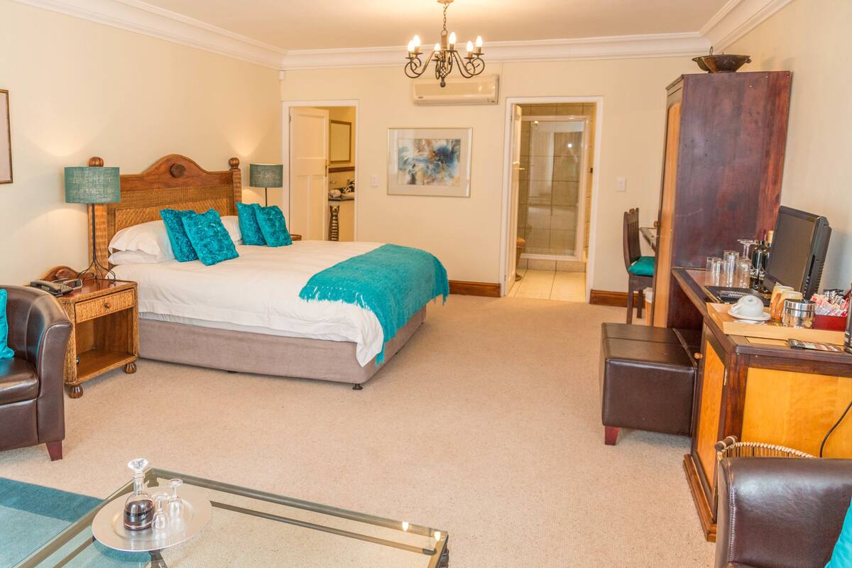 A hotel room with a bed, a desk, a chair, a nightstand, and a mirror.