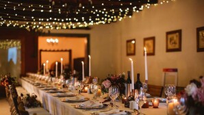 Una larga mesa de comedor decorada con velas, copas y arreglos florales, evocando una experiencia gastronómica formal.