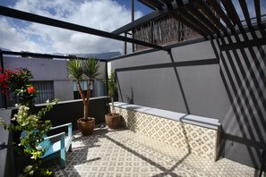 A balcony with potted plants, a blue bench, and patterned tiles. - The Grey Hotel (Cape Town)