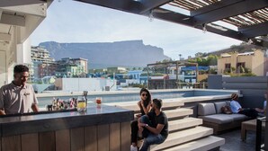 A rooftop bar with a view of a cityscape and mountains.