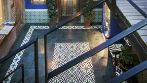 A multi-level interior with a central staircase, tiled floors, and potted plants.