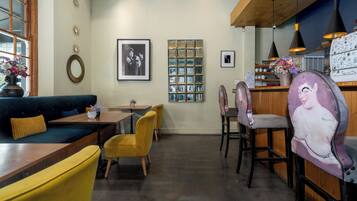 Un restaurante con zona de bar, techo de madera y una disposición de asientos que incluye un sofá y sillas.