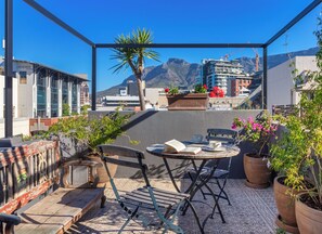 A rooftop terrace with a table, chairs, and potted plants. - The Grey Hotel (Cape Town)