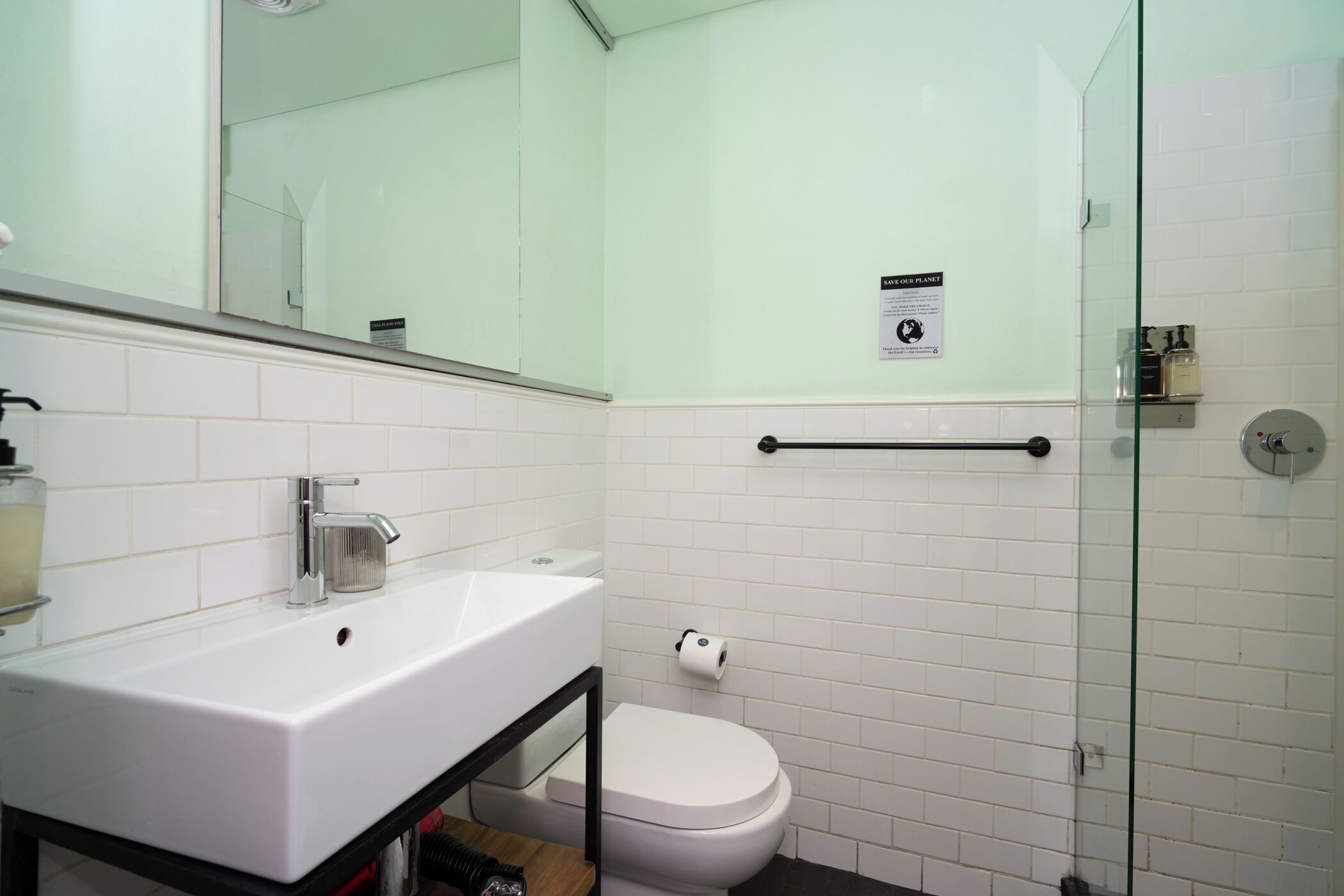 Un bany modern amb un lavabo blanc, vàter i una cabina de dutxa amb envidriament.