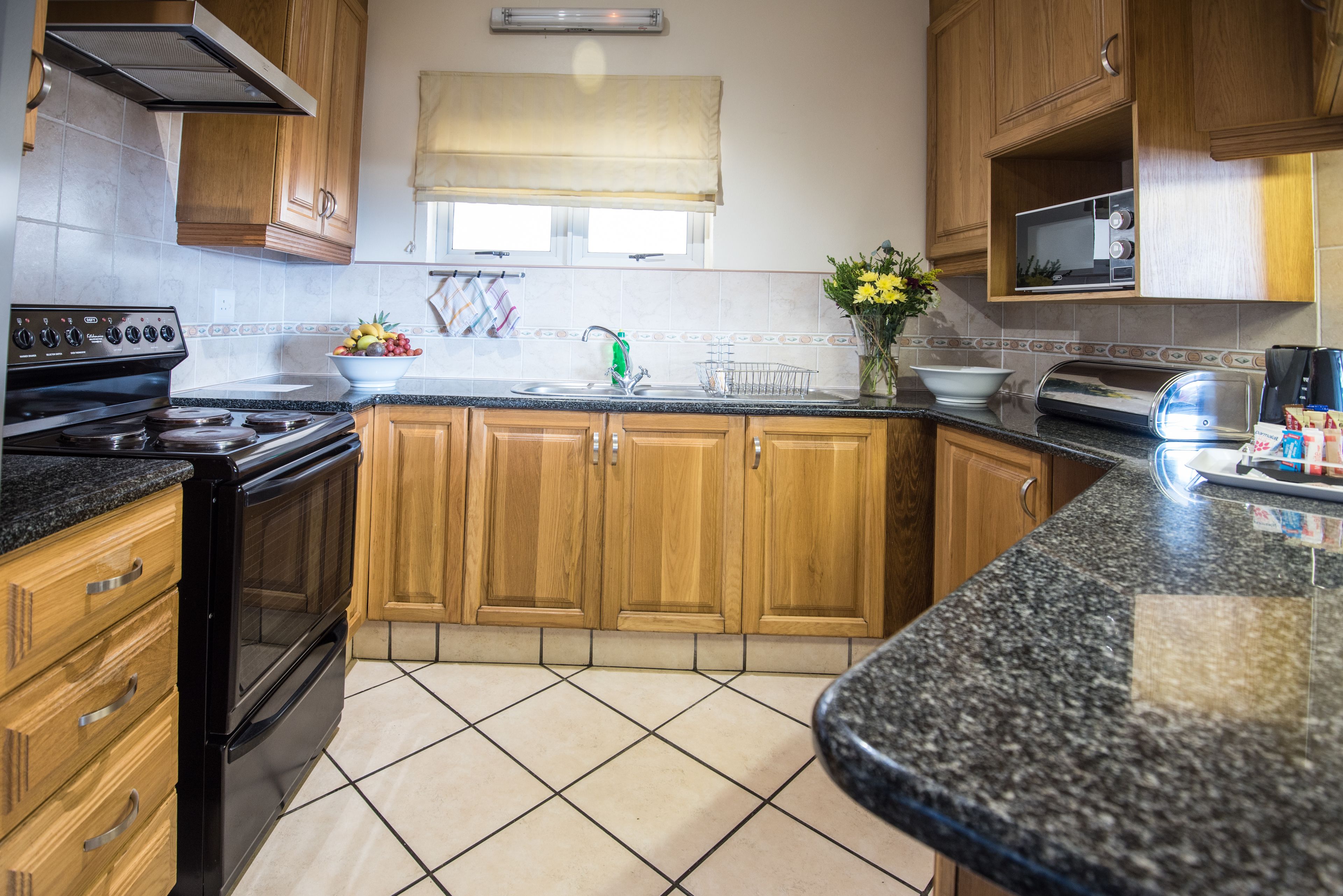 A kitchen with wooden cabinets, a black stove, a microwave, and a sink.