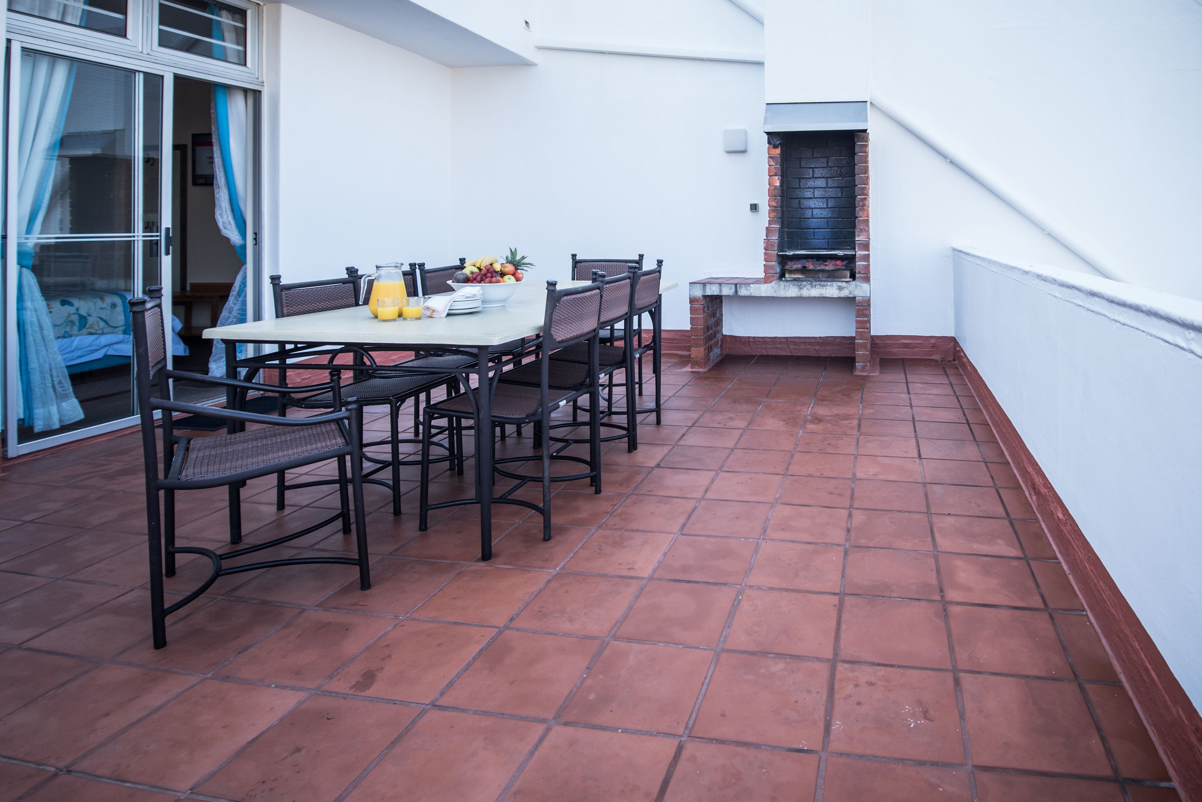 A patio with a table and chairs, a grill, and a sliding glass door.