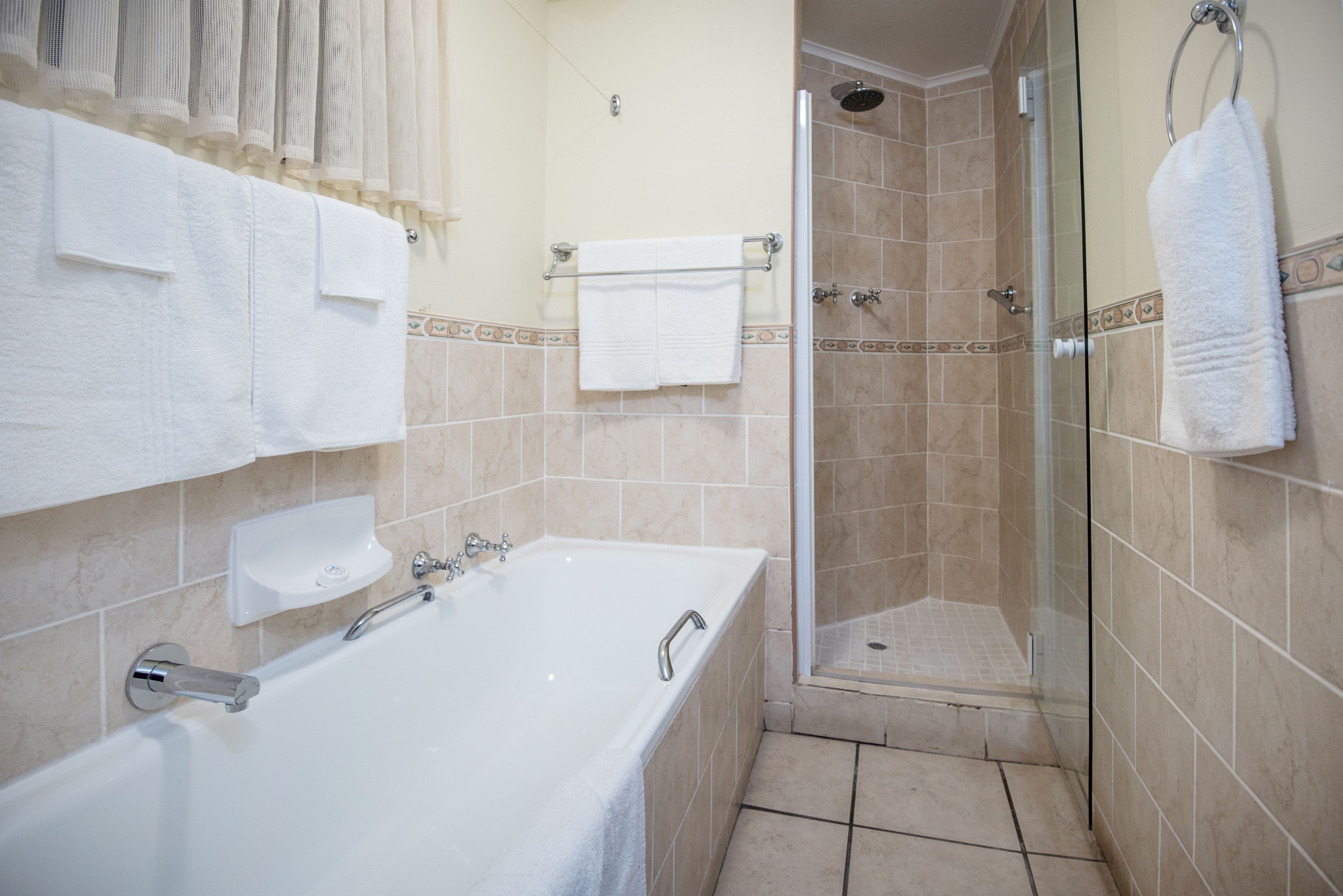 A bathroom with a bathtub, a glass shower enclosure, and a towel rack.