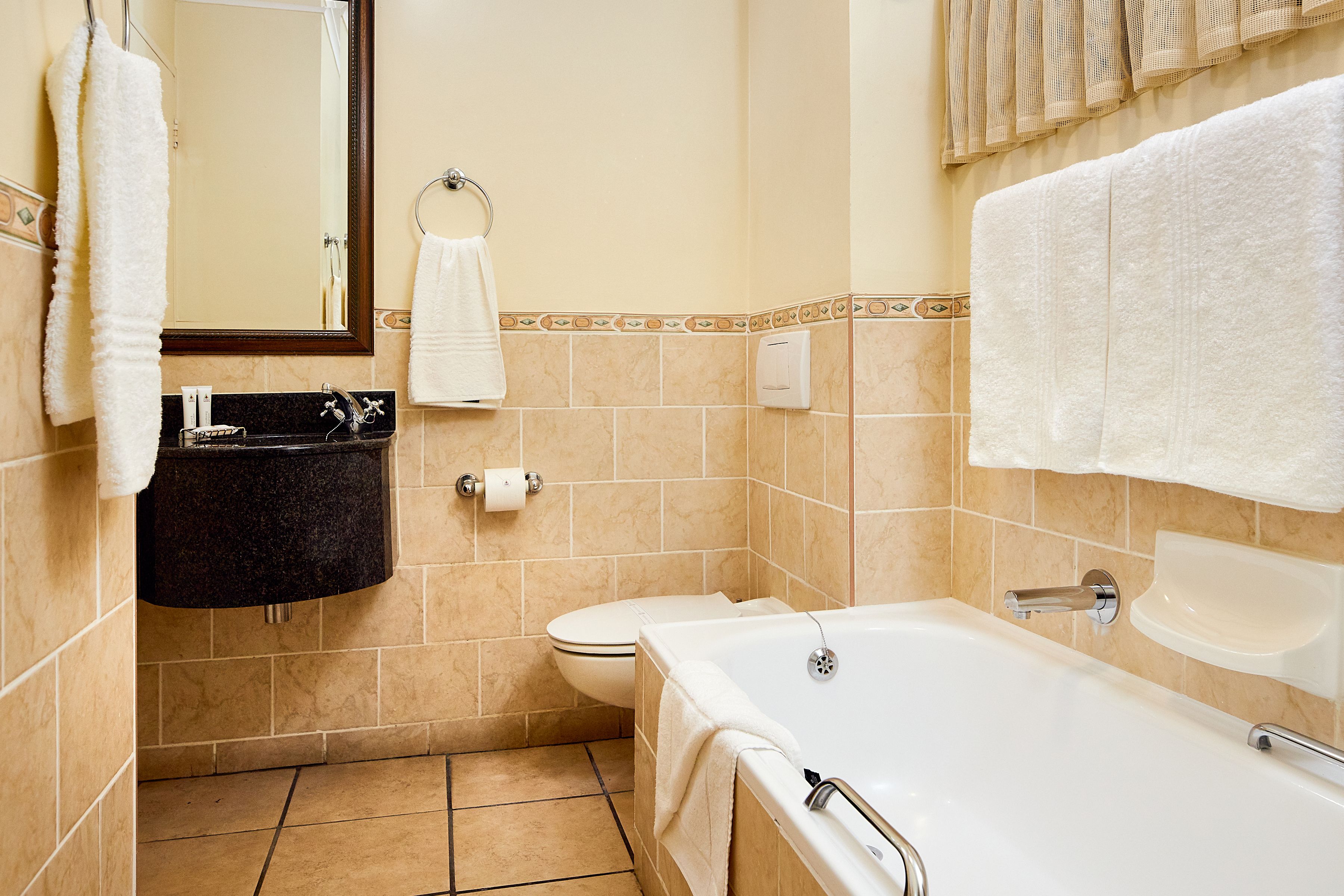 A bathroom with a bathtub, toilet, sink, and mirror.