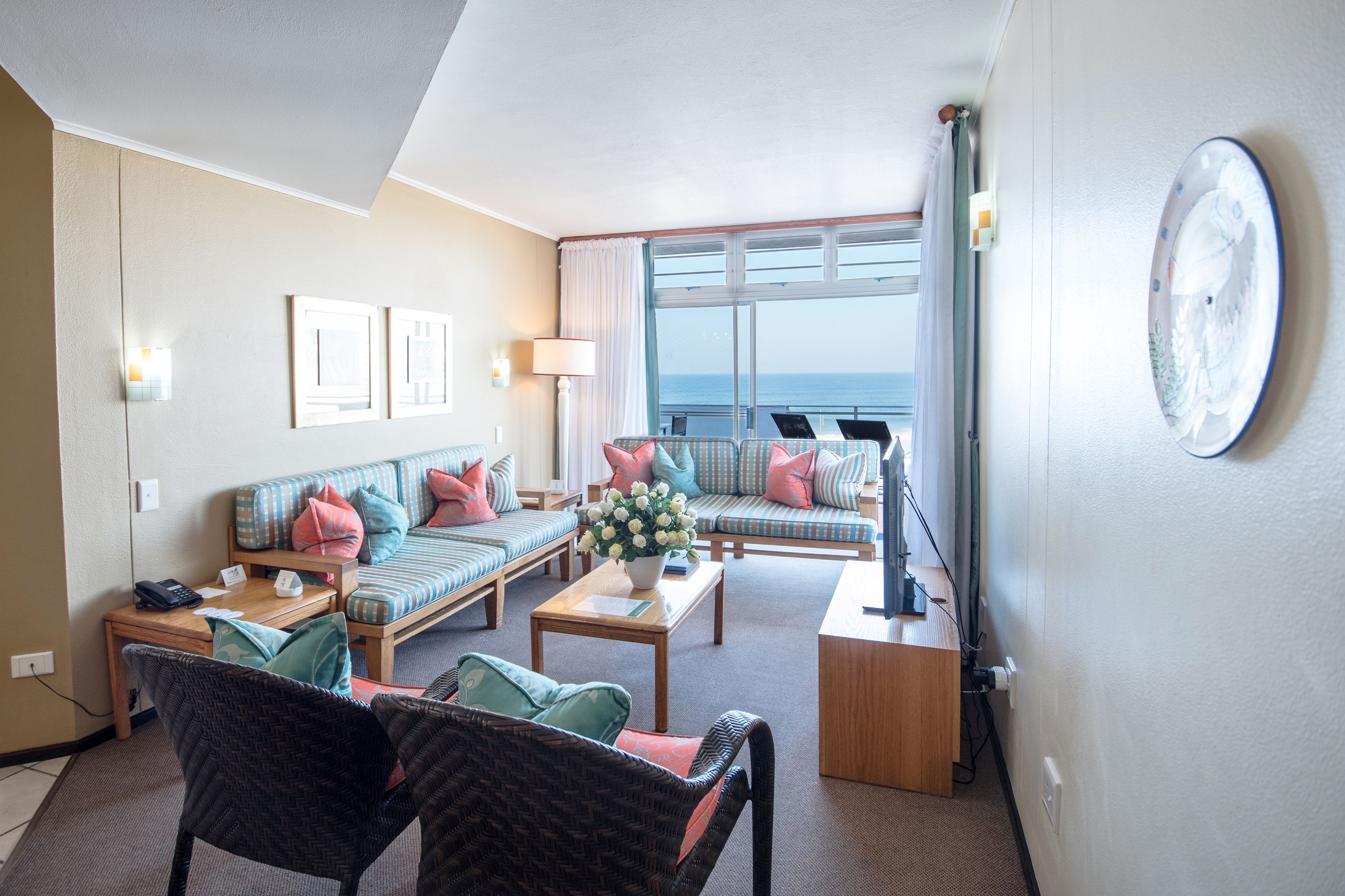 Habitación de hotel con balcón, dos sofás, una mesa de centro y televisor.