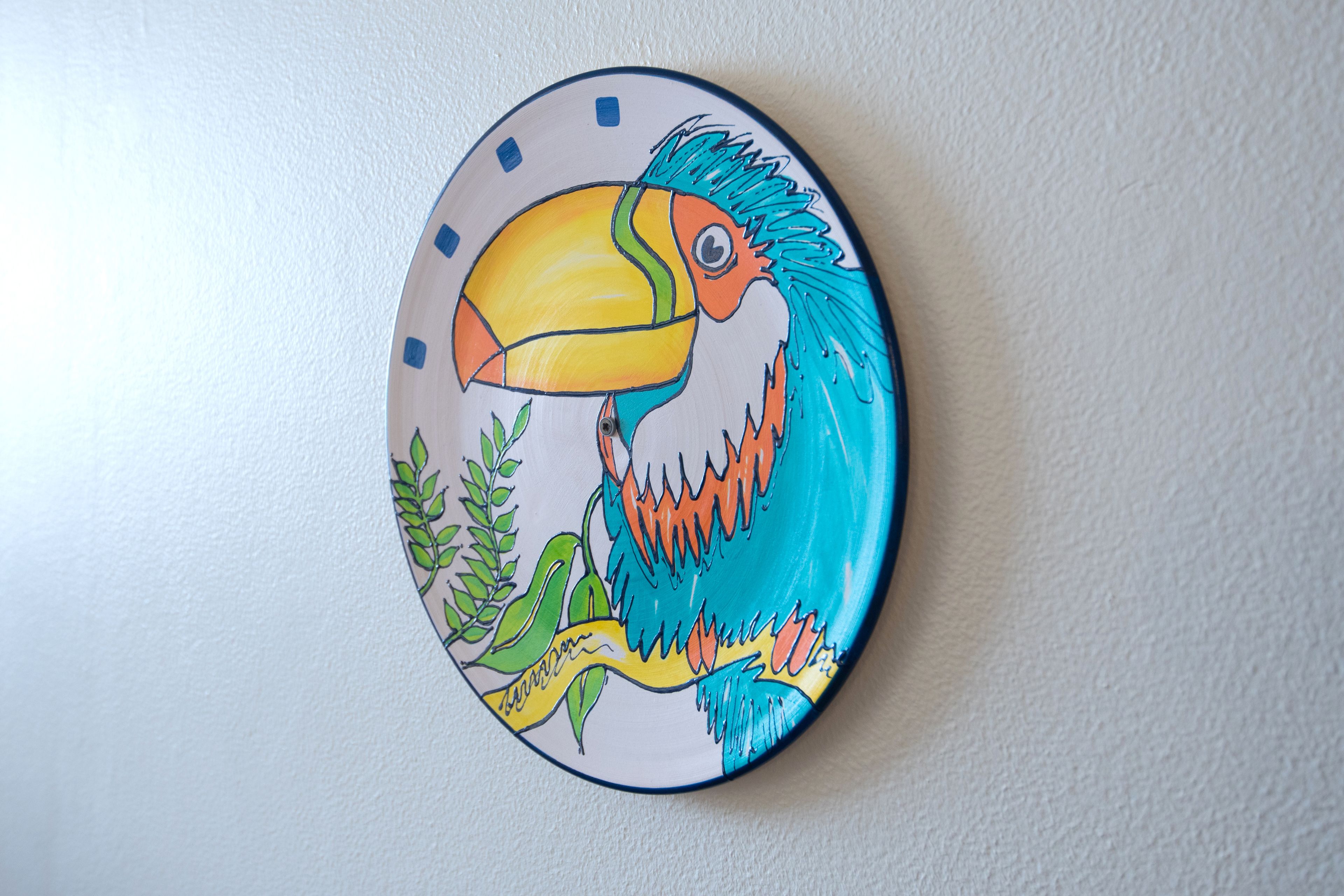 A wall-mounted plate with a colorful toucan illustration.