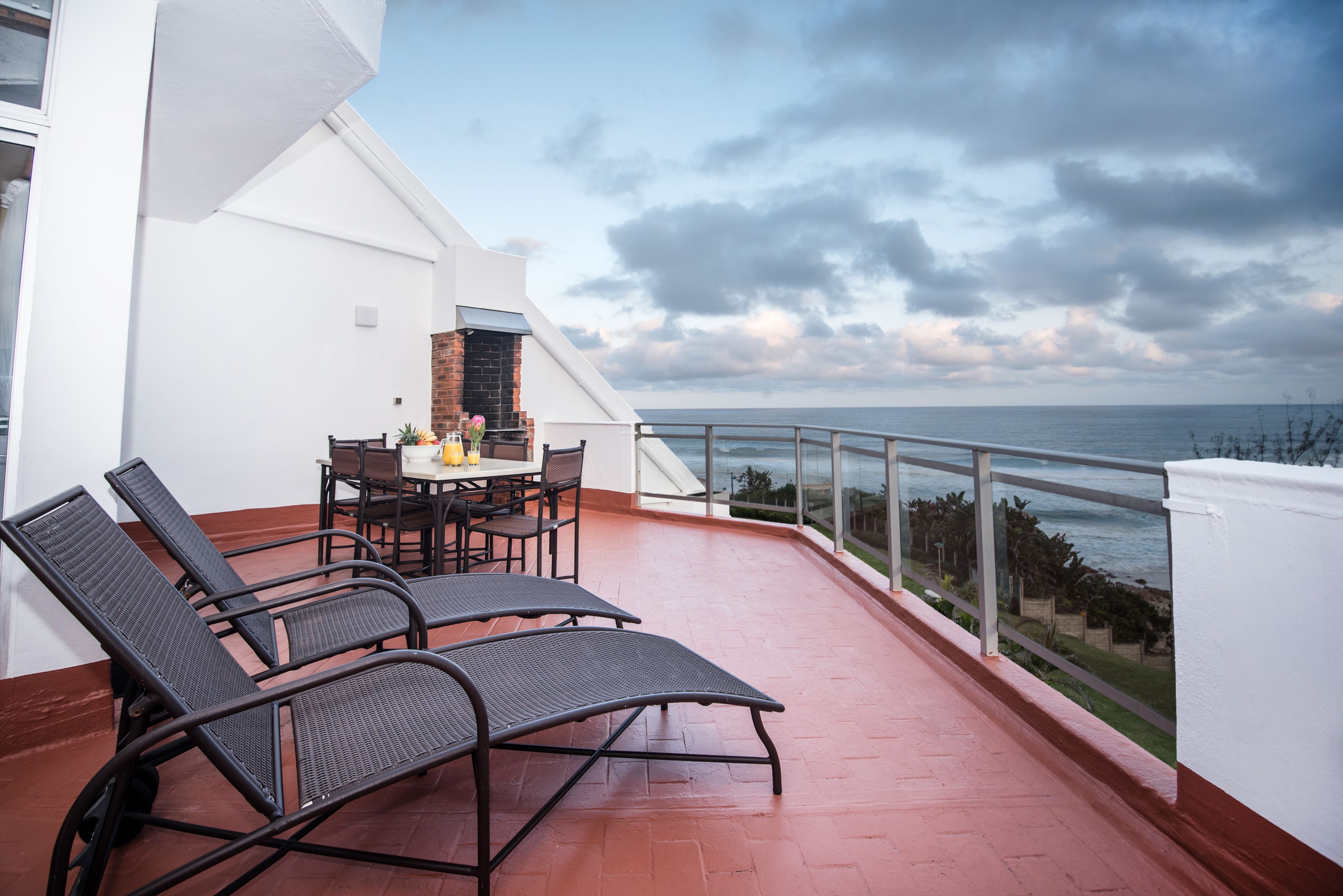 Un balcon avec deux fauteuils, une table et un barbecue.
