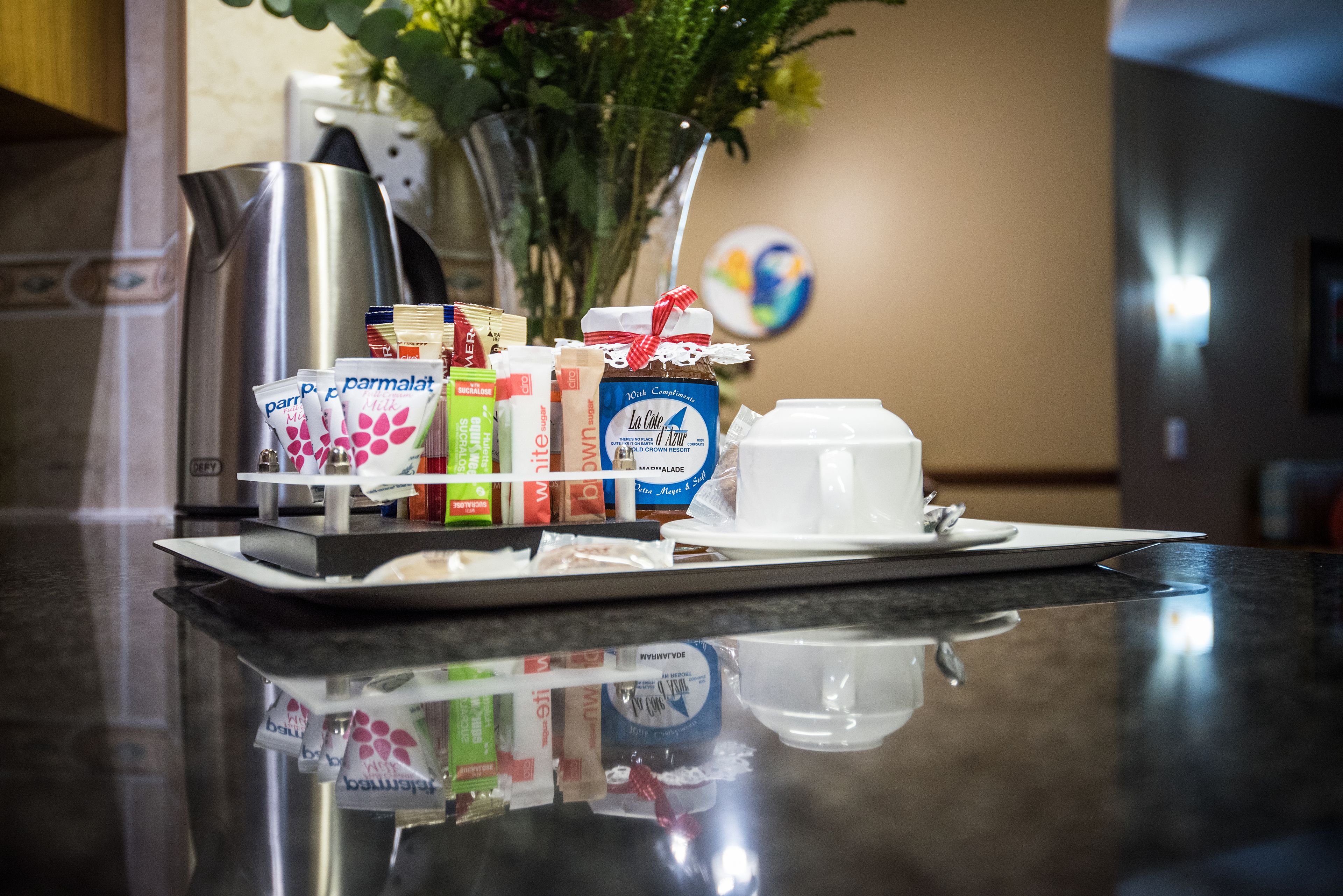 A tray with food items and a cup on a reflective countertop.