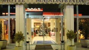 The entrance of Hotel Majadahonda with a Christmas tree and potted plants. - Hotel Majadahonda (Majadahonda)