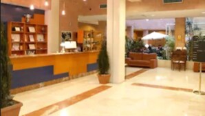 A hotel lobby with a reception desk, seating area, and potted plants. - Hotel Majadahonda (Majadahonda)