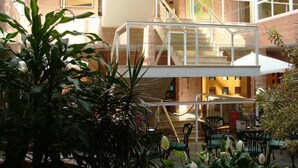 A multi-level atrium with a glass staircase, indoor plants, and seating areas. - Hotel Majadahonda (Majadahonda)