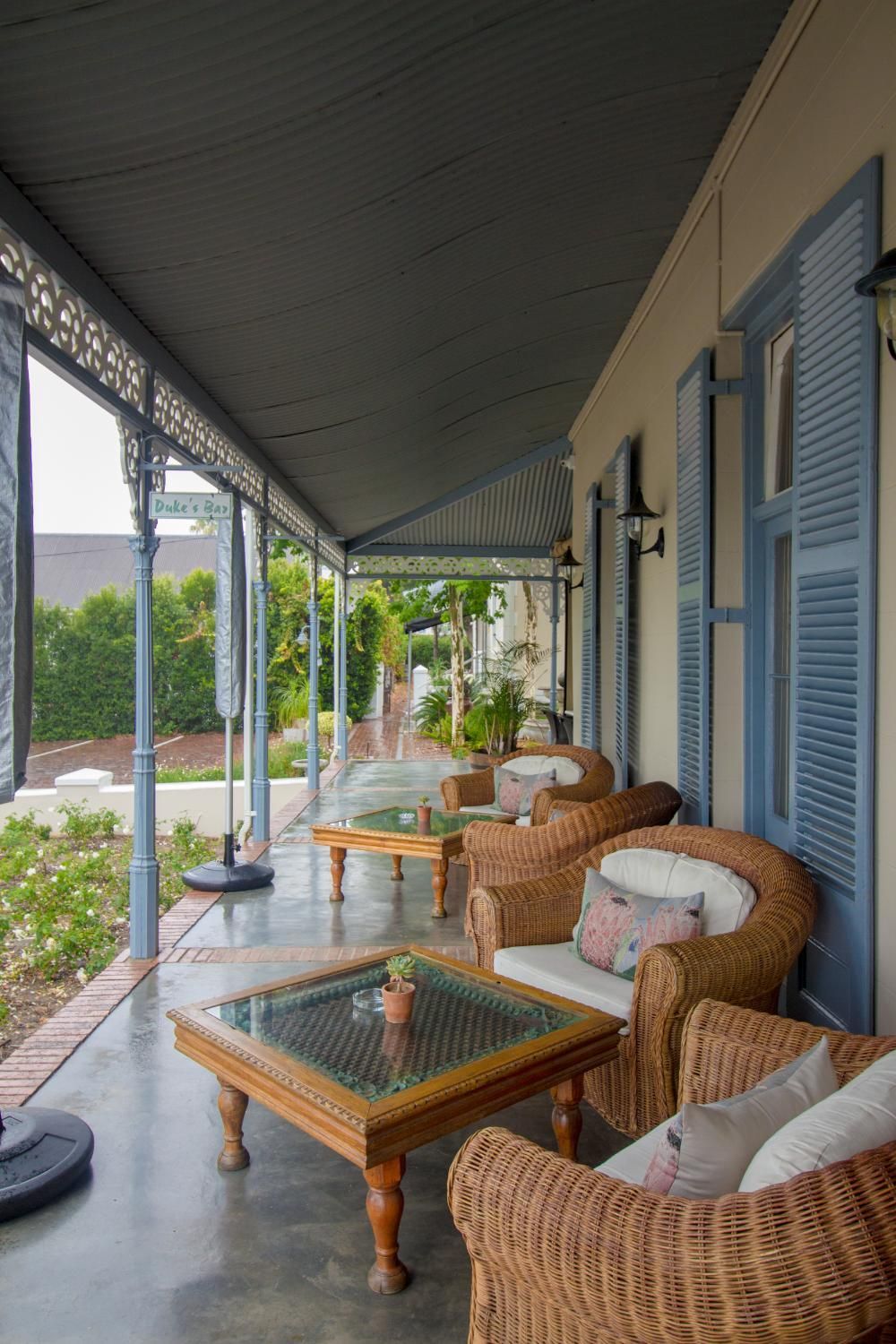A covered outdoor seating area with wicker furniture and a glass-top table.