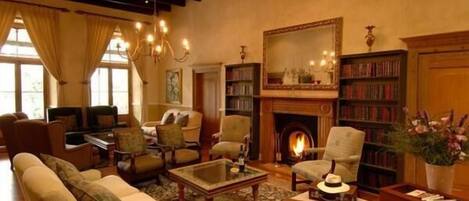 A cozy living room with a fireplace, comfortable seating, and a bookshelf.