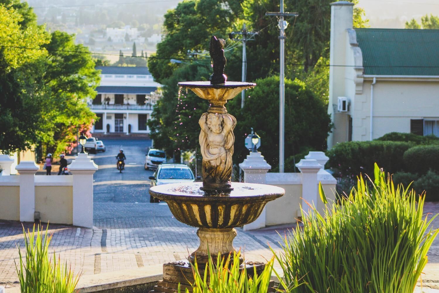 A fountain with a statue in the center, surrounded by greenery.