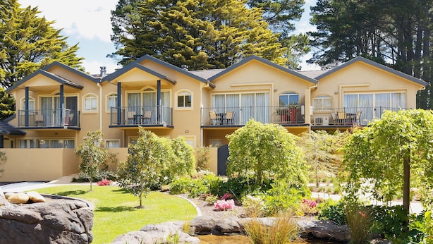 A multi-story hotel with balconies, a landscaped garden, and a small pond. - Falls Mountain Retreat (Wentworth Falls)