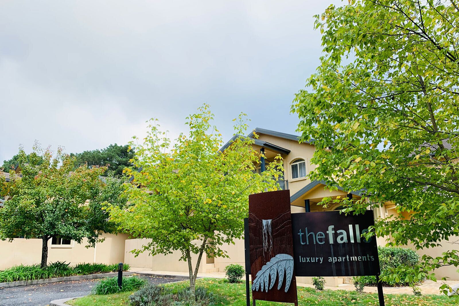 A sign for 'The Fall' luxury apartments with a modern building in the background.