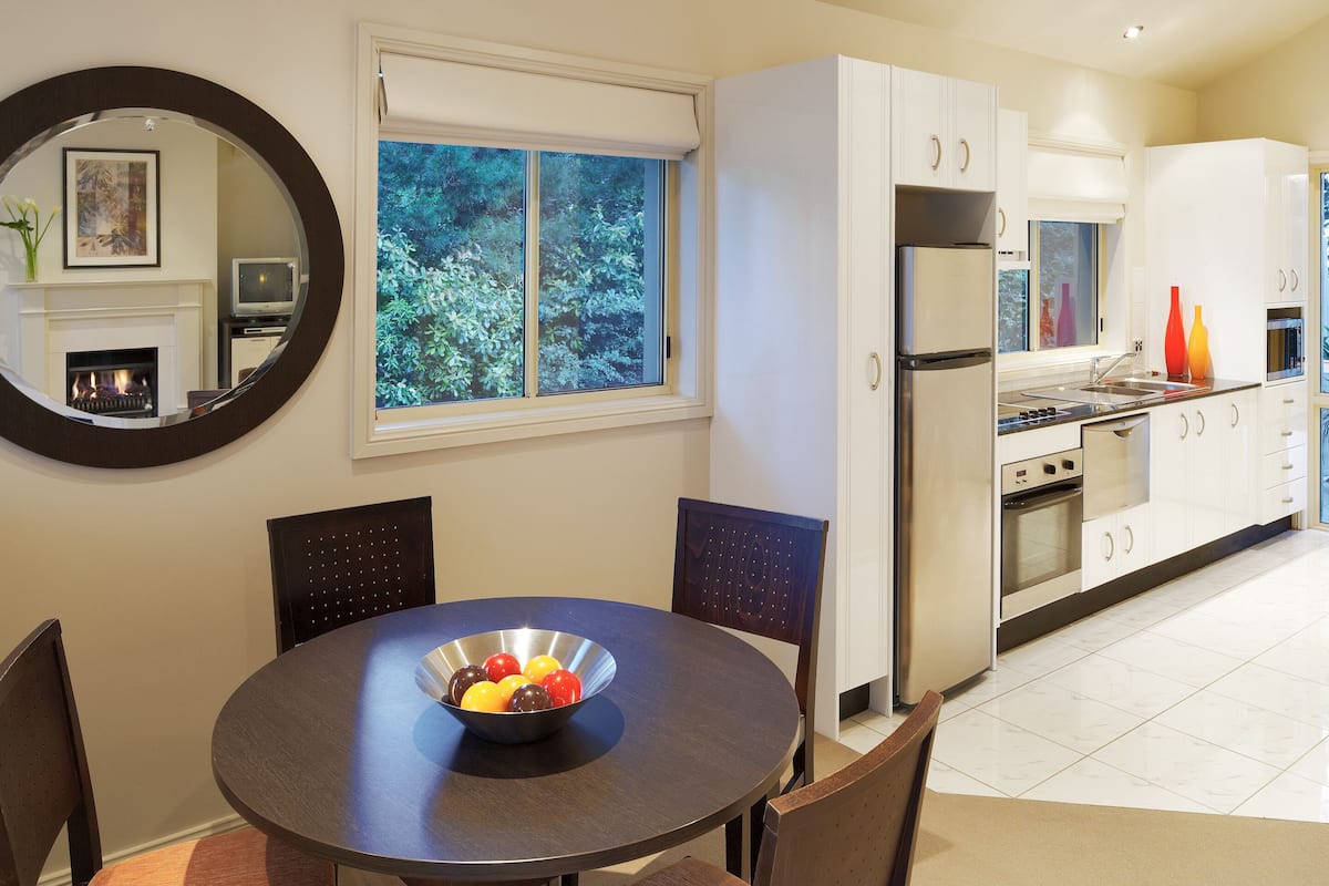 A modern kitchen with white cabinets, stainless steel appliances, and a dining area with a round table and chairs.