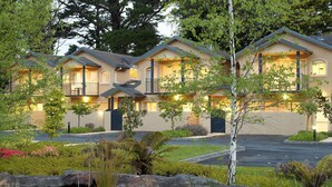A hotel with multiple balconies, a landscaped garden, and a pond. - Falls Mountain Retreat (Wentworth Falls)