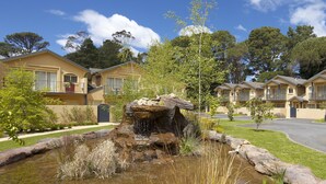 A residential area with multiple two-story houses, a small pond with a waterfall, and a well-maintained lawn. - Falls Mountain Retreat (Wentworth Falls)