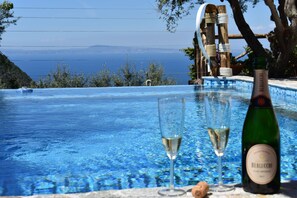 A pool with clear blue water, two glasses of white wine, and a bottle of wine on the edge. - B&B Casa Mazzola (Sant'Agnello)