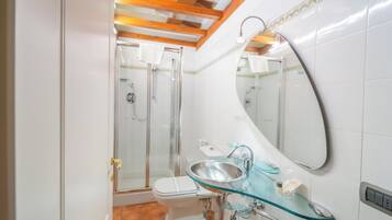 Un baño con cabina de ducha de vidrio, lavamanos de vidrio y un espejo grande.
