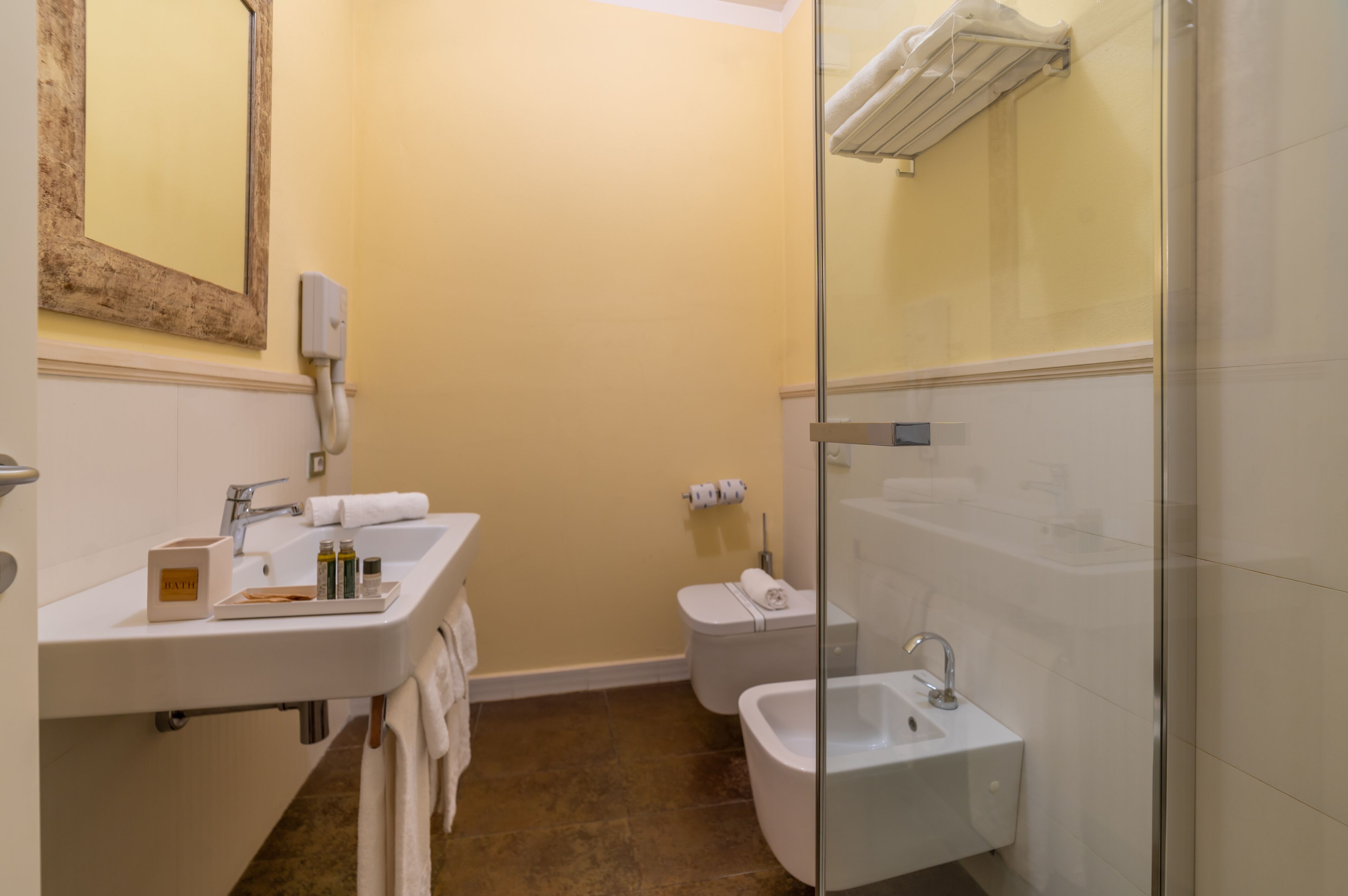 A bathroom with a sink, mirror, toilet, and bidet.