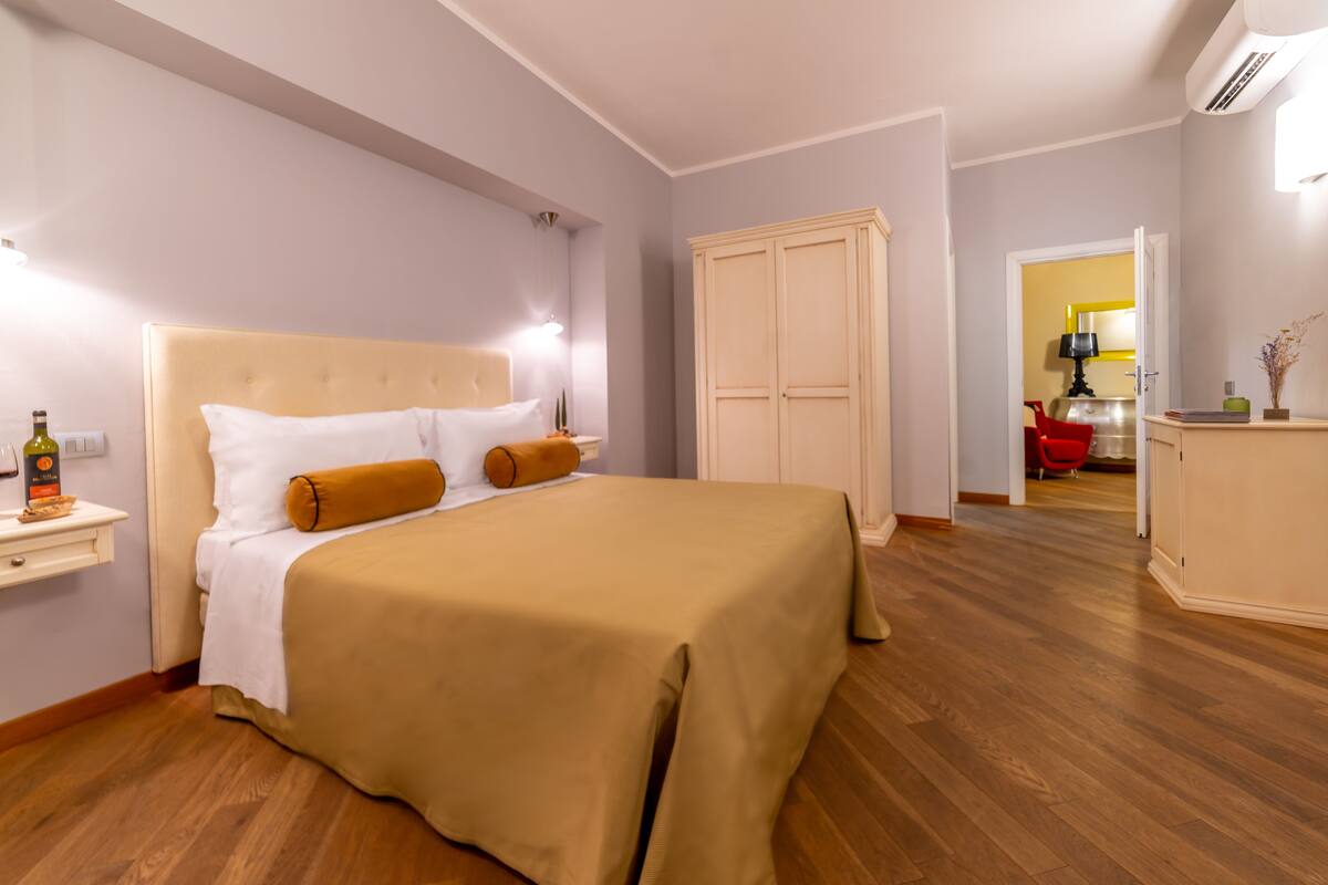 A bedroom with a large bed, a bedside table, a wardrobe, and a mirror.