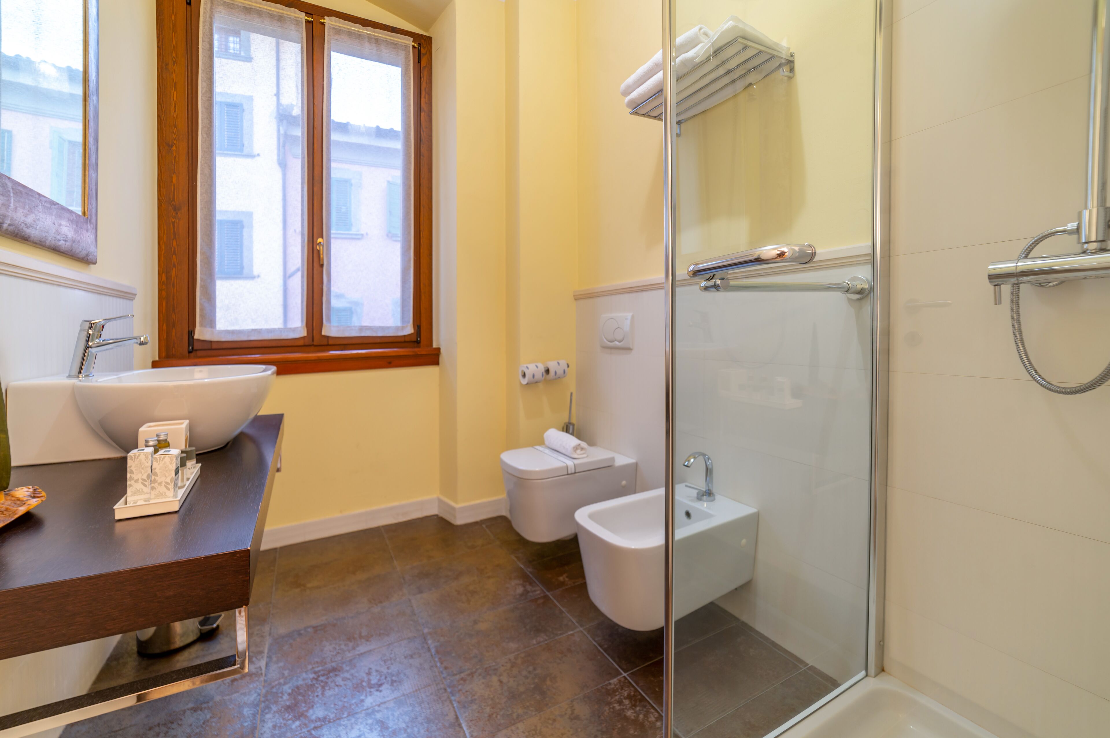 A modern bathroom with a large sink, toilet, bidet, and glass-enclosed shower.