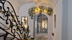 A hallway with a stone archway, a decorative metal railing with lemons, and a wall-mounted light fixture. - La Conca Azzurra (Conca dei Marini)