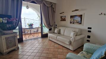 Suite, vista al mar | Área de sala de estar | Televisión LCD