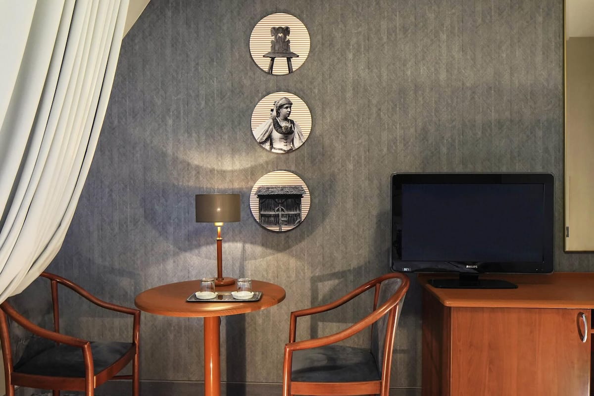 Une chambre d’hôtel avec une table ronde, deux chaises, un téléviseur et trois éléments de décoration murale de forme circulaire.