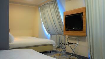 Habitación de hotel con dos camas, un televisor montado en la pared y un equipo de aire acondicionado.